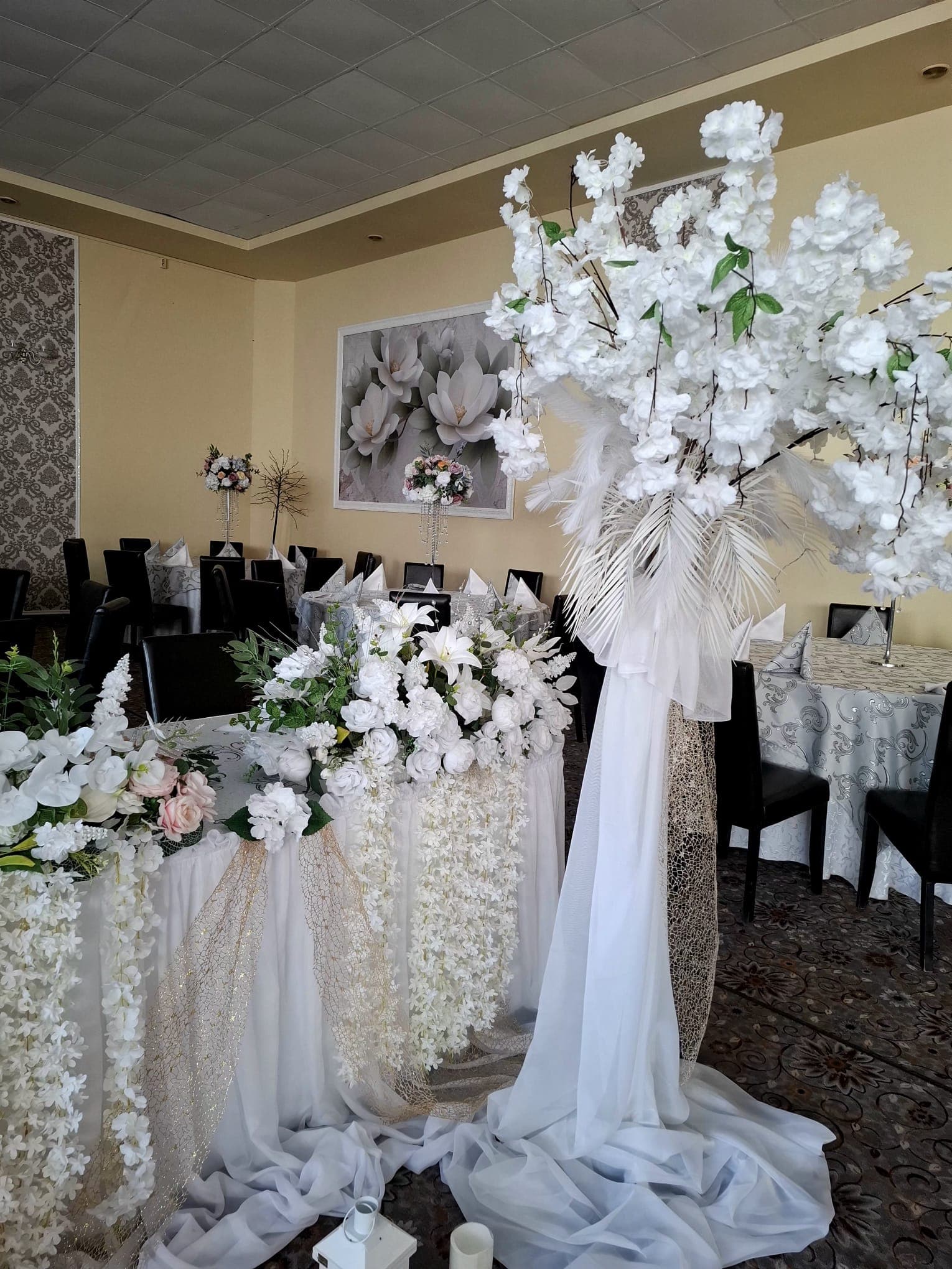 Masă festivă cu flori albe și scaune negre în salonul intim