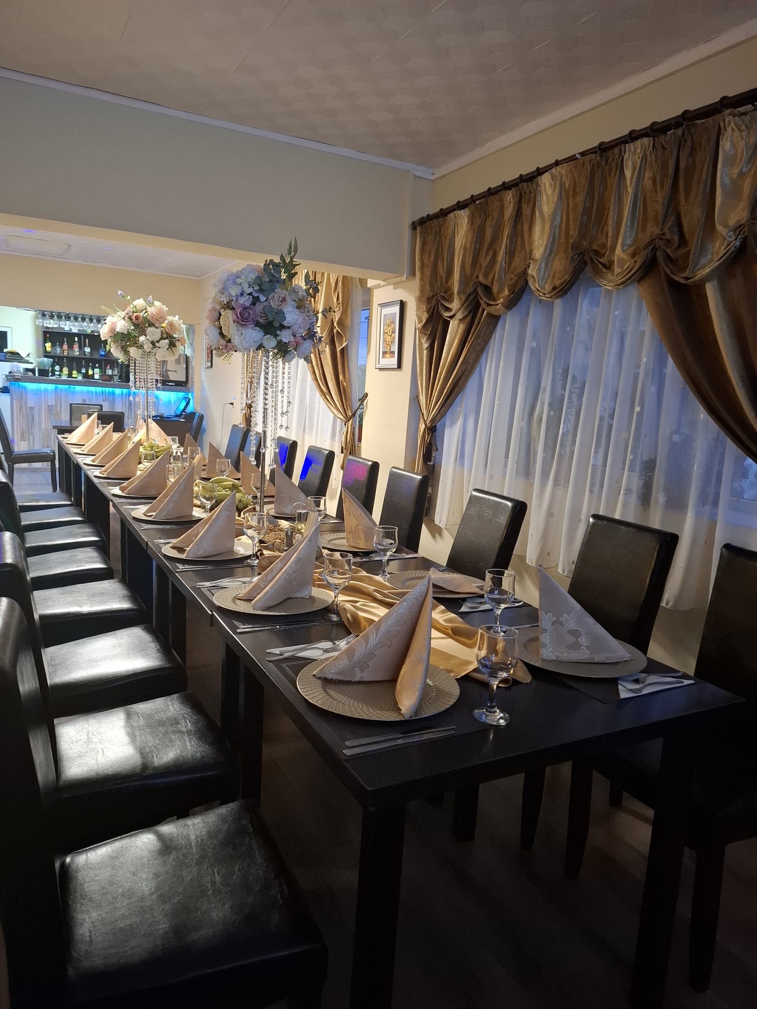 Salon intim Restaurant Ardealul cu masă lungă, scaune negre și aranjament floral