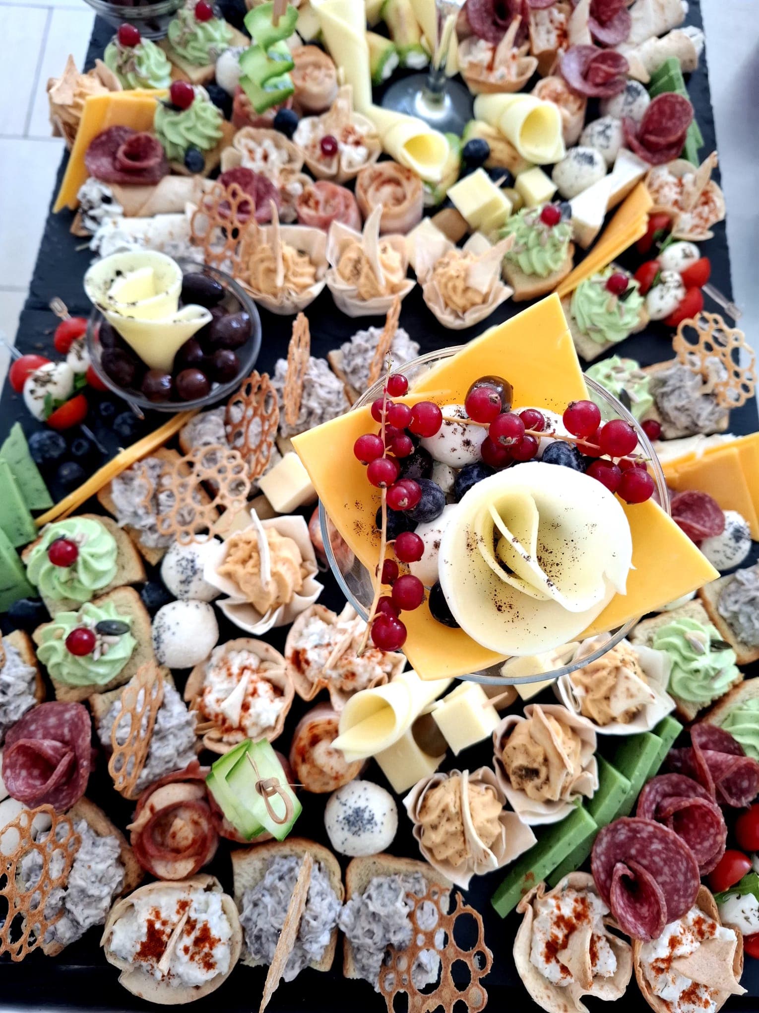 Platou festiv de aperitive văzut de sus, cu canapele și mezeluri