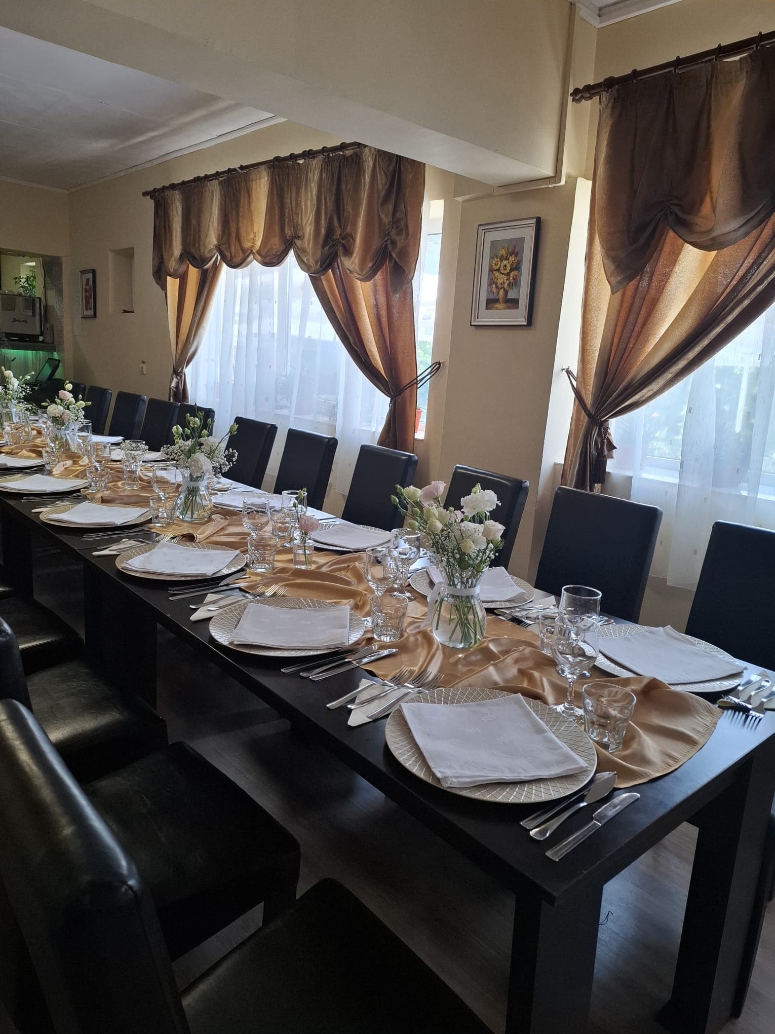 Salon intim pregătit cu runner auriu, flori albe și scaune negre